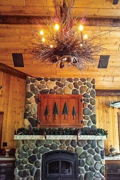 a stone fireplace in a wood paneled room with lights on the ceiling and decorations above it