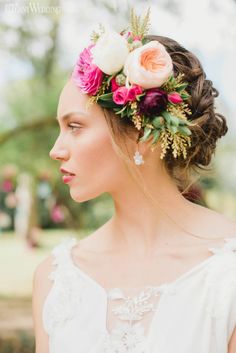 a woman with flowers in her hair wearing a white dress and floral headpieces