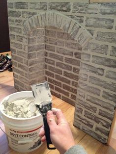 a person is painting a brick fireplace with white paint