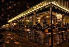 an outdoor cafe at night with rain falling on the ground