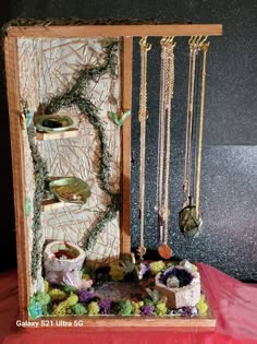 a wooden box with jewelry hanging from it's sides and plants growing out of it