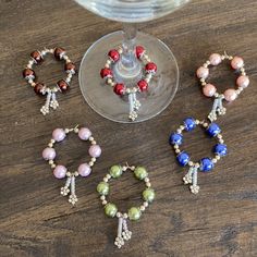 three wine glasses with beaded bracelets next to each other on a wooden table