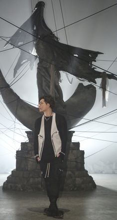 a man standing in front of a statue with wires hanging from it's sides