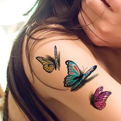 a woman's arm with three colorful butterflies on the back of her shoulder and chest