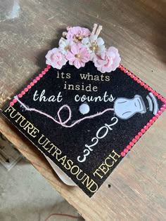 a decorated graduation cap on top of a wooden table with flowers and writing that reads, it's what inside that counts