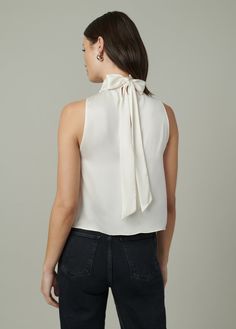 Sleeveless, high neck top with shirred neckline and back scarf tie for versatile styling. DETAILS + FIT High neckline Sleeveless Shirred scarf tie Back keyhole opening Silky satin with the perfect drape. 100% PolyesterMoa is 5’10” and is wearing a size Small Waist: 25” Bust: 33” Hips: 35.5” Elegant Sleeveless Tie Back Blouse, Elegant Sleeveless Tie-back Blouse, Elegant Sleeveless Blouse With Tie Back, Elegant High Neck Silk Top, Chic Silk Tie Back Top, Chic Silk Tops With Tie Back, Silk Tie-back Top For Evening, Silk Tie Back Top For Evening, Fitted Satin Tie Neck Top