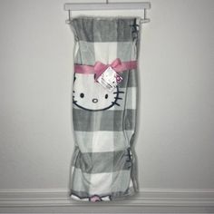 a hello kitty blanket hanging on a wall with a pink bow around the neck and bottom