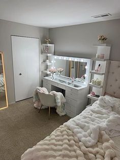 a bedroom with a bed, dresser and dressing table in front of a large mirror