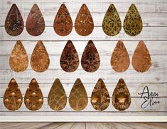 a group of brown and gold tear shaped earrings on top of a wooden table next to a white wall