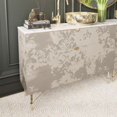 a white and gold dresser in a room with green plants on the sideboard next to it