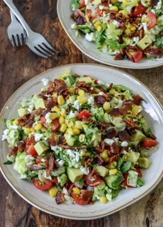 two plates filled with salad on top of a wooden table