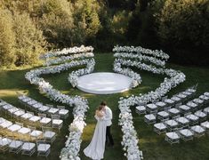 a bride and groom standing in front of an outdoor wedding ceremony set up with white flowers