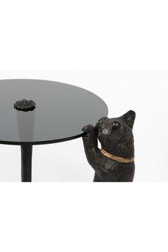 a black table with a bear figurine on it's legs and a glass top