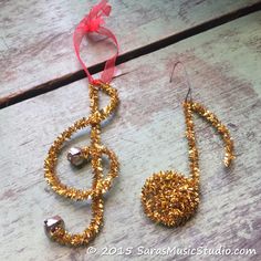 a musical note ornament made out of gold glitters and beads with a red ribbon