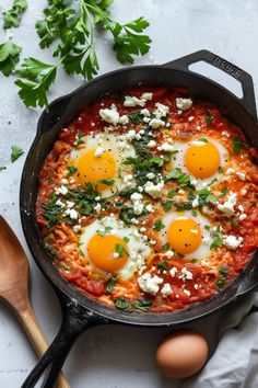 two eggs are in a skillet with tomato sauce and parsley on the side