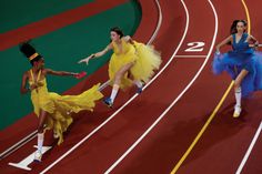 three women in yellow dresses running on a track