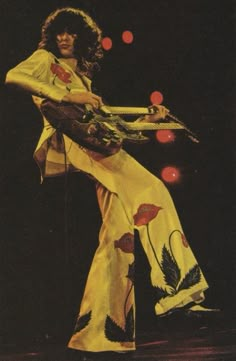 an image of a woman that is on stage with a guitar and wearing a long dress