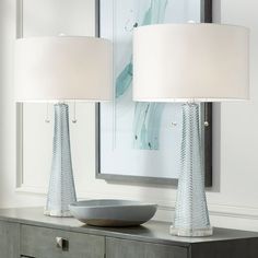 two lamps sitting on top of a table next to a bowl with a light on it