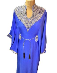 Step into elegance with this royal blue kaftan, designed to make a statement at any event. The luxurious fabric is complemented by intricate gold embroidery that adorns the neckline, sleeves, and waist, showcasing a blend of traditional craftsmanship and modern style. The kaftan features a high, embellished neckline and a delicate, adjustable waist tie with tassels, ensuring a perfect fit for all body types. The rich blue colour is striking and versatile, making it suitable for both daytime and Dress Nikah, Islamic Wedding Dress, Blue Kaftan, Nikah Dress, Embroidered Kaftan, Embellished Neckline, Islamic Wedding, Eid Gift, Gold Embroidery