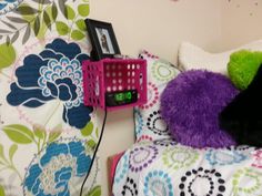 a purple alarm clock sitting on top of a bed next to a purple stuffed animal