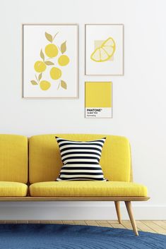 a yellow couch sitting in front of two pictures on the wall next to a blue rug