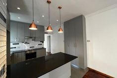 a kitchen with an island and three lights hanging from it's ceiling over the stove