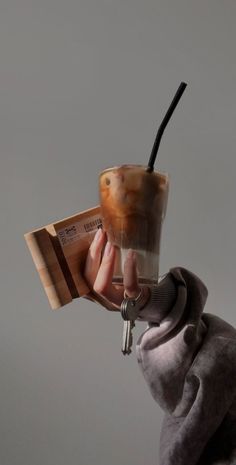 a person holding a coffee cup in their hand with a keychain attached to it