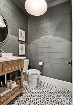 a white toilet sitting next to a sink in a bathroom under a round light fixture