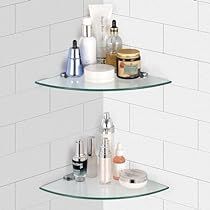 two glass shelves in the corner of a white tiled wall with various items on them