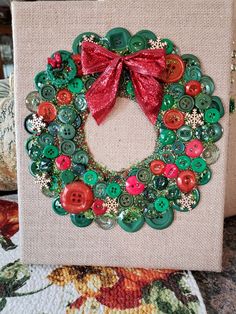 a christmas wreath made out of buttons on a canvas