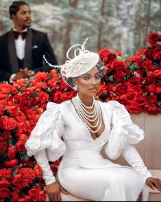 a woman sitting on top of a bench wearing a white dress and headpiece with pearls