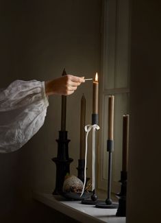 a person lighting a candle on top of a table next to other candles and decorations