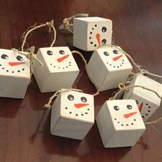 four snowmen made out of toilet paper and twine on a wooden table with string