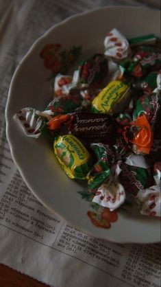 a white bowl filled with assorted candy on top of a table