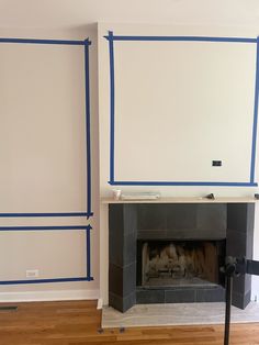 a fireplace with blue tape around it in a room that has been painted white and is being worked on