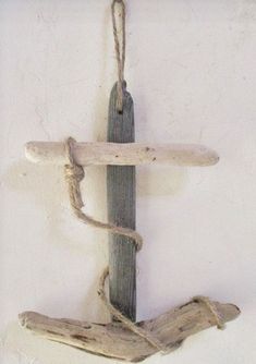 a piece of driftwood hanging from a rope on a white wall with a wooden stick attached to it