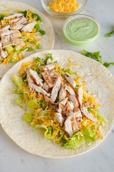 two tortillas with chicken, lettuce and cheese on them sitting on a table