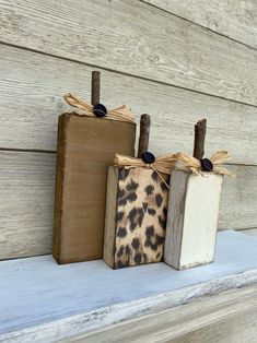 three wooden boxes with handles are sitting on a shelf next to each other, one is decorated with leopard print and the other has a bow