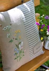 a pillow with flowers on it sitting on a bench next to a potted plant