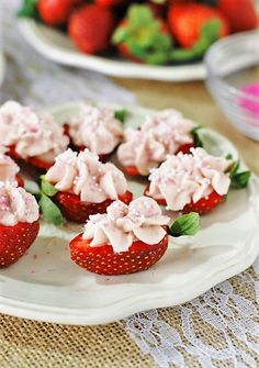 strawberry cupcakes with white frosting and green leaves on a plate, ready to be eaten