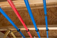 several different colored umbrellas hanging from the ceiling in a room with plywood boards