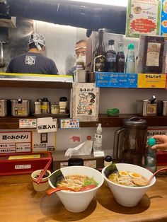 two bowls of soup are sitting on the counter in front of a man at a restaurant