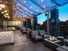 an outdoor patio with seating and fire pit in the middle of it, overlooking a cityscape