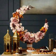 a table topped with flowers and cookies on top of a wooden table next to a gold candle