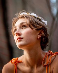 a woman wearing an orange dress and a flower in her hair looking off into the distance