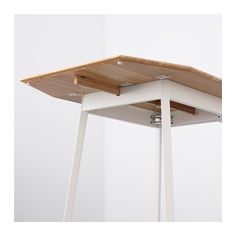 a white and wood table with two legs on it's sides, against a white wall