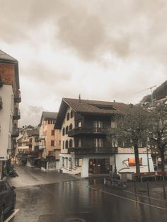 a rainy day in the city with buildings and cars parked on the side of the road