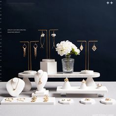 a table with jewelry on it and white flowers in a vase next to the stand