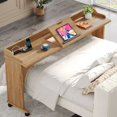 a bed with a laptop on top of it next to a table that has an open drawer