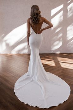 a woman in a white dress standing on a wooden floor with her back to the camera